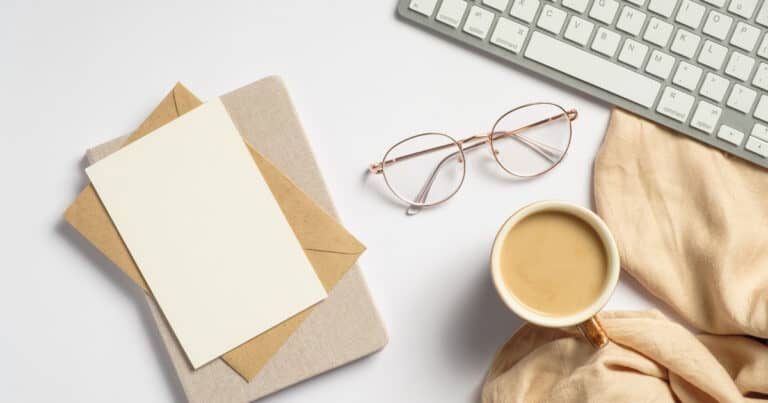 Desk with keyboard, books, glasses, coffee, and fabric