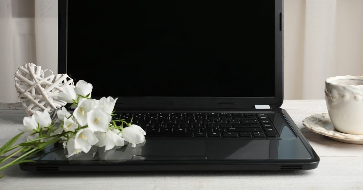 Desk with laptop, coffee, and flowers
