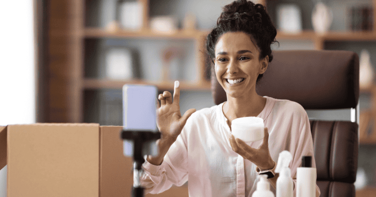 Woman holding beauty products up to her computer