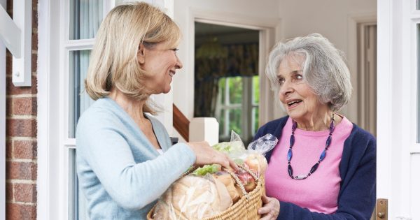 Women helping a senior woman with groceries