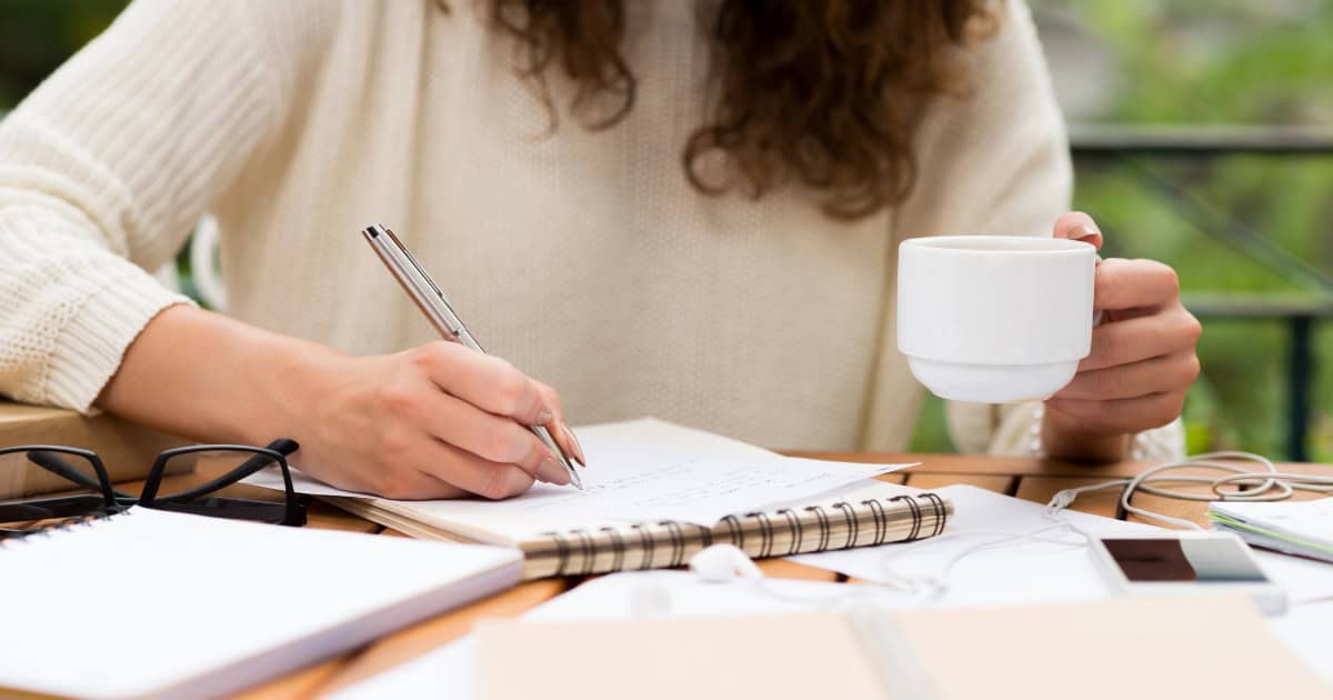 Woman holding a cup and writing