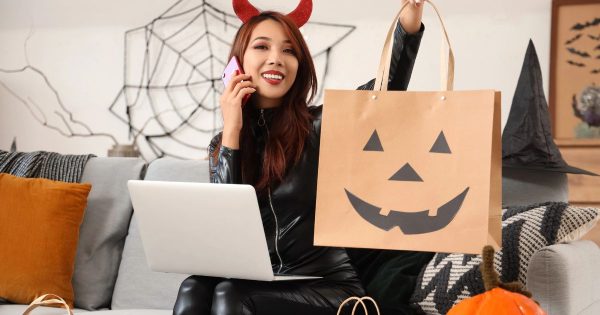 Woman dressed in a Halloween costume holding a laptop